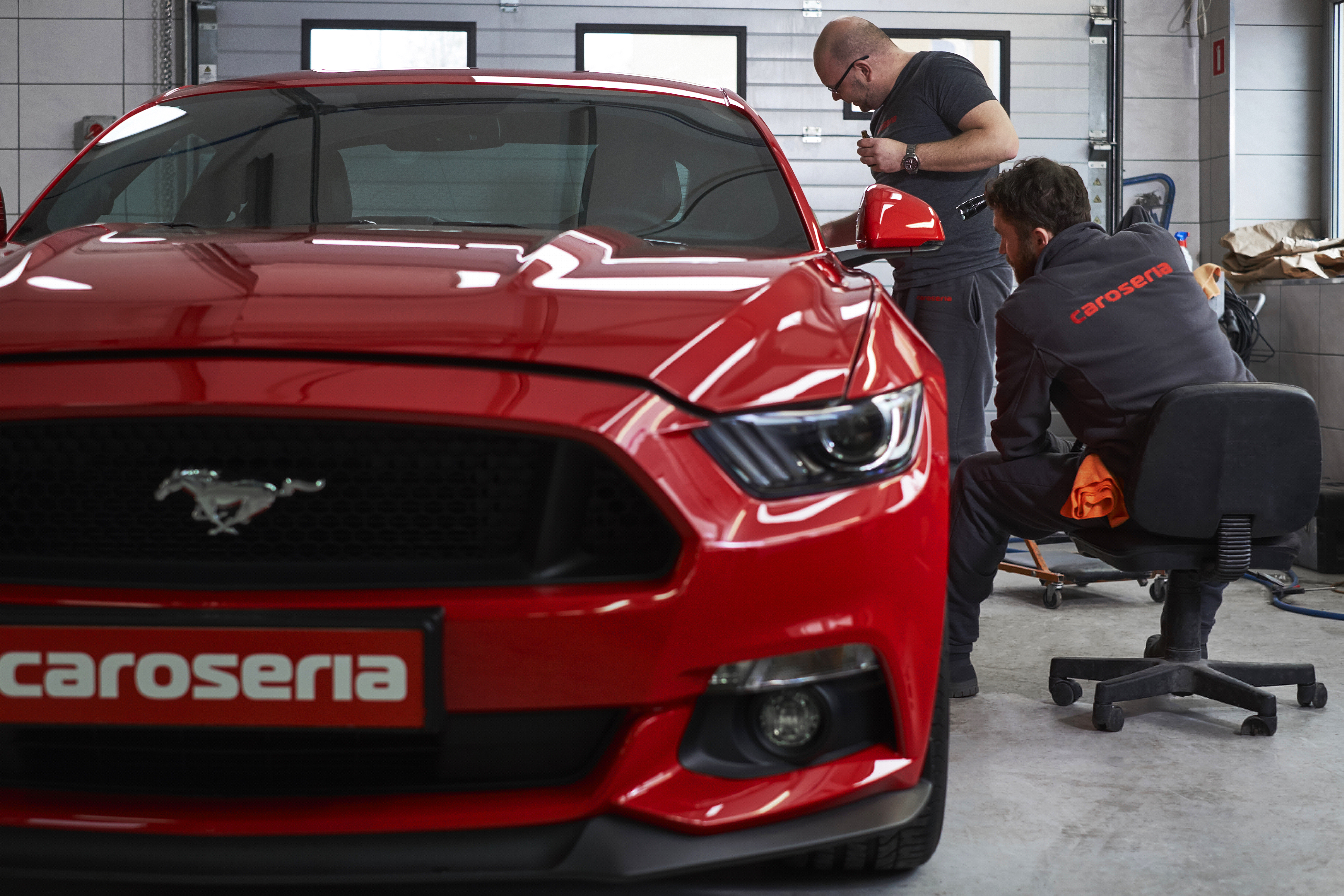 Detailers refining a red sports car in studio