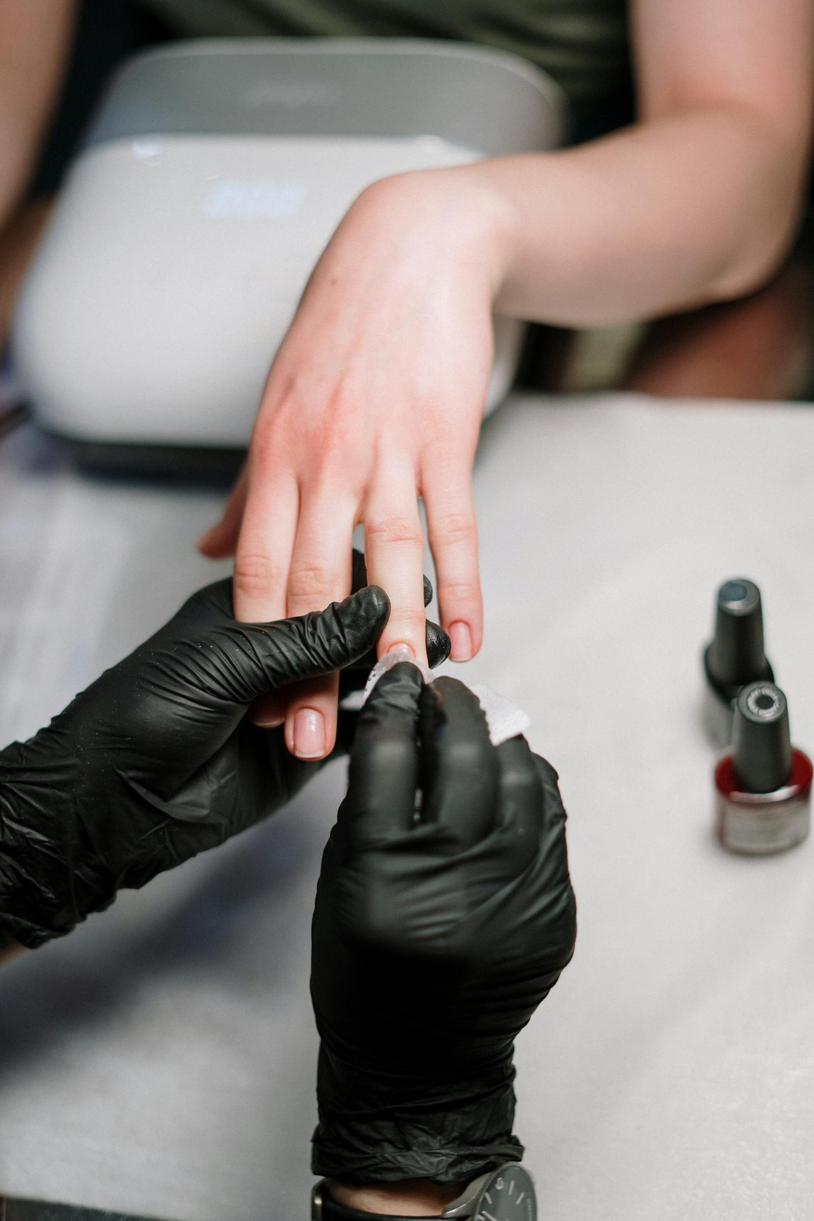 Close-up of manicure process with black gloves.