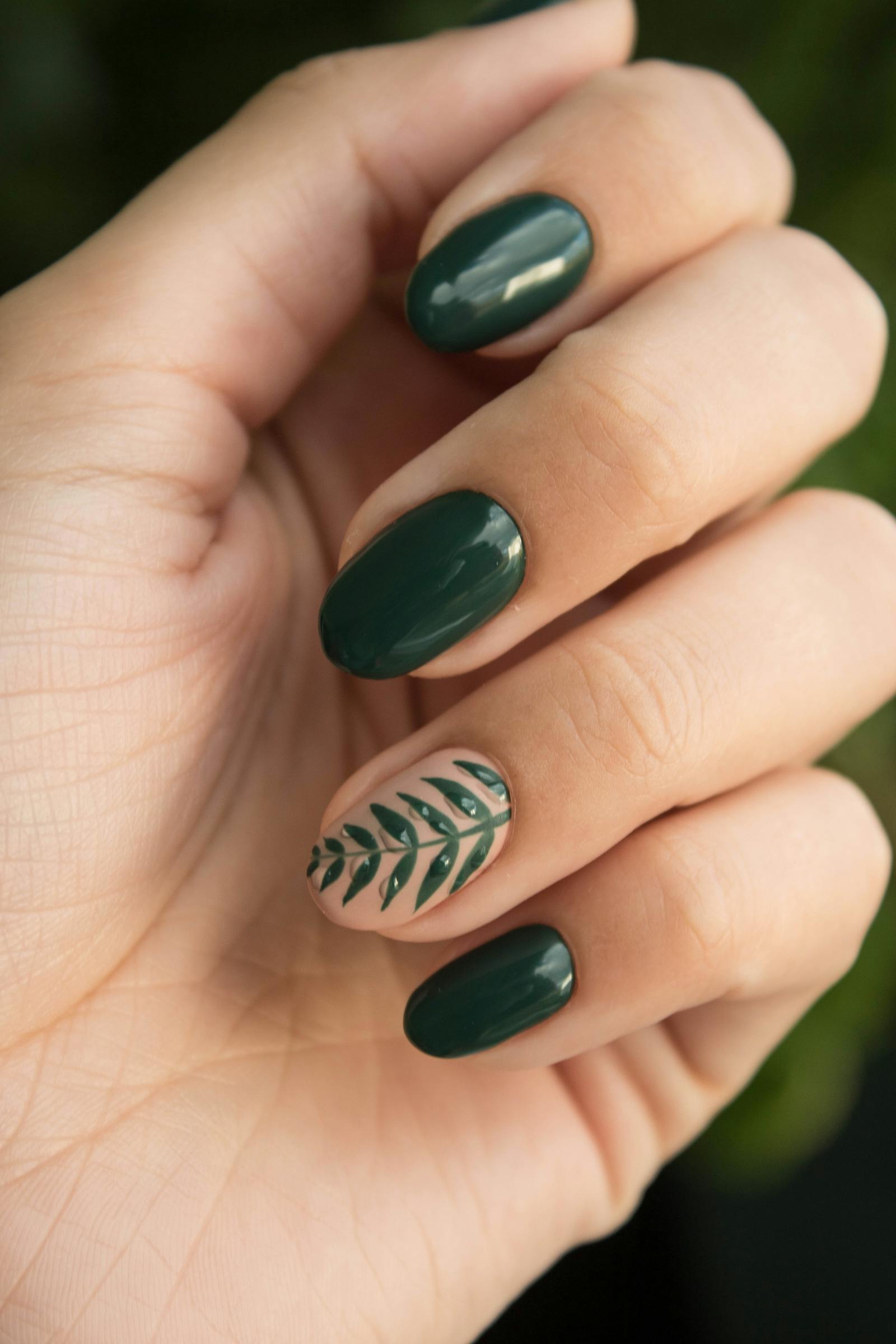 Green nail design with leaf accent art.