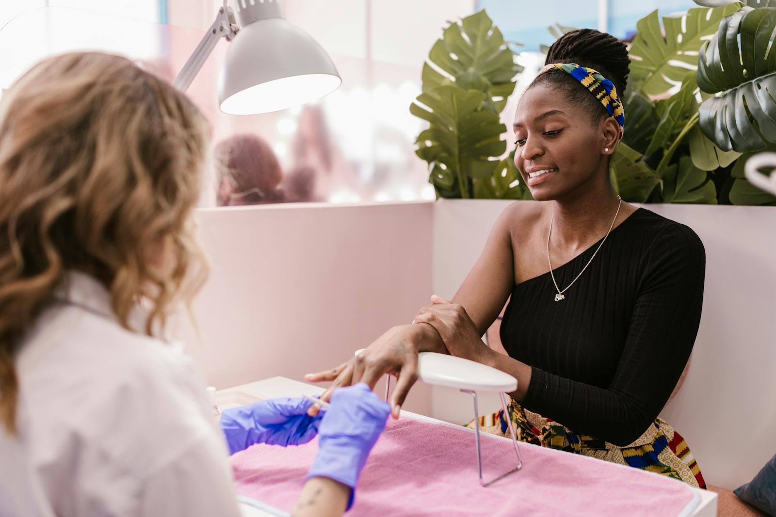 Client receiving manicure service in a bright nail salon.